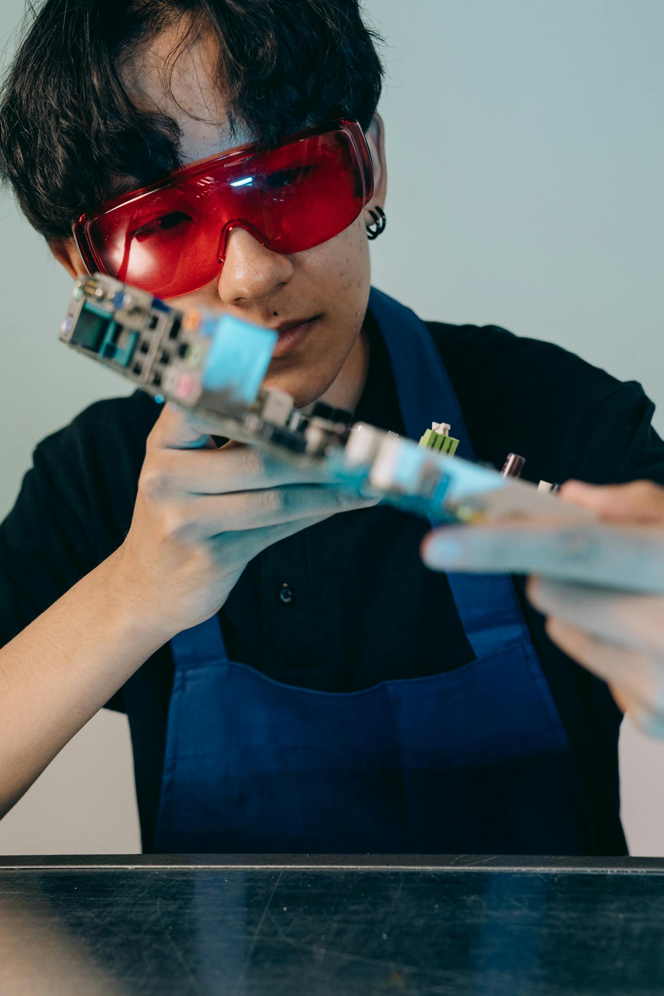 A focused technician inspects a motherboard, showcasing attention to detail in electronic repair.